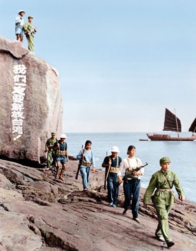Soldados civiles de la República Popular China en Xiamen, Fujian, patrullando la costa, en la década de los años 1960. Las palabras en la roca dicen "Liberaremos a Taiwán