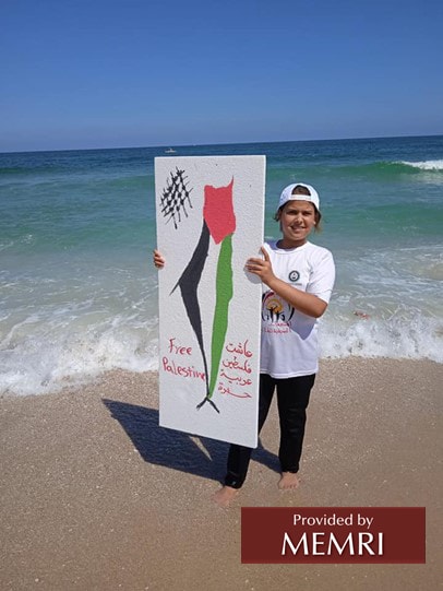 Chica en el campamento Khan Younis sostiene un mapa de Palestina desde el río hasta el mar, junto al texto en árabe "Larga vida a la Palestina árabe y libre" y el texto en inglés "Palestina libre" (Facebook.com/hcyspalestine, 28 de julio, 2022)