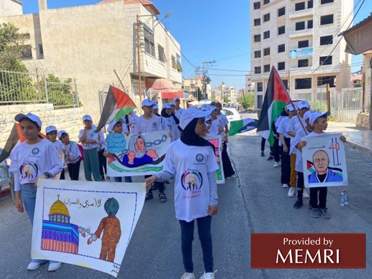 Campistas en Tulkarm marchan con pancartas que estos hicieron de terroristas palestinos encarcelados, incluyendo a Karim Younis e Israa Ja'abis, quien cumple una sentencia de 11 años por perpetrar una operación terrorista en el año 2016 (Facebook.com/hcyspalestine, 29 de julio, 2022)